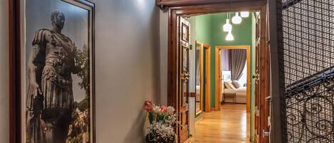 A hallway with a framed statue, a vase of flowers, and a sign above a door.