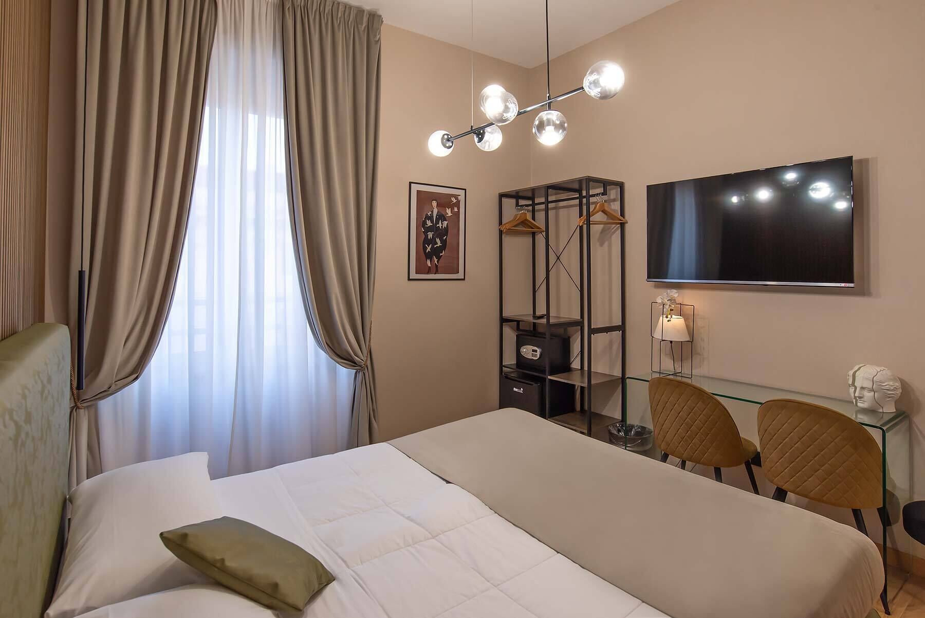 A hotel room with a bed, a TV, a desk with chairs, and a mirror.