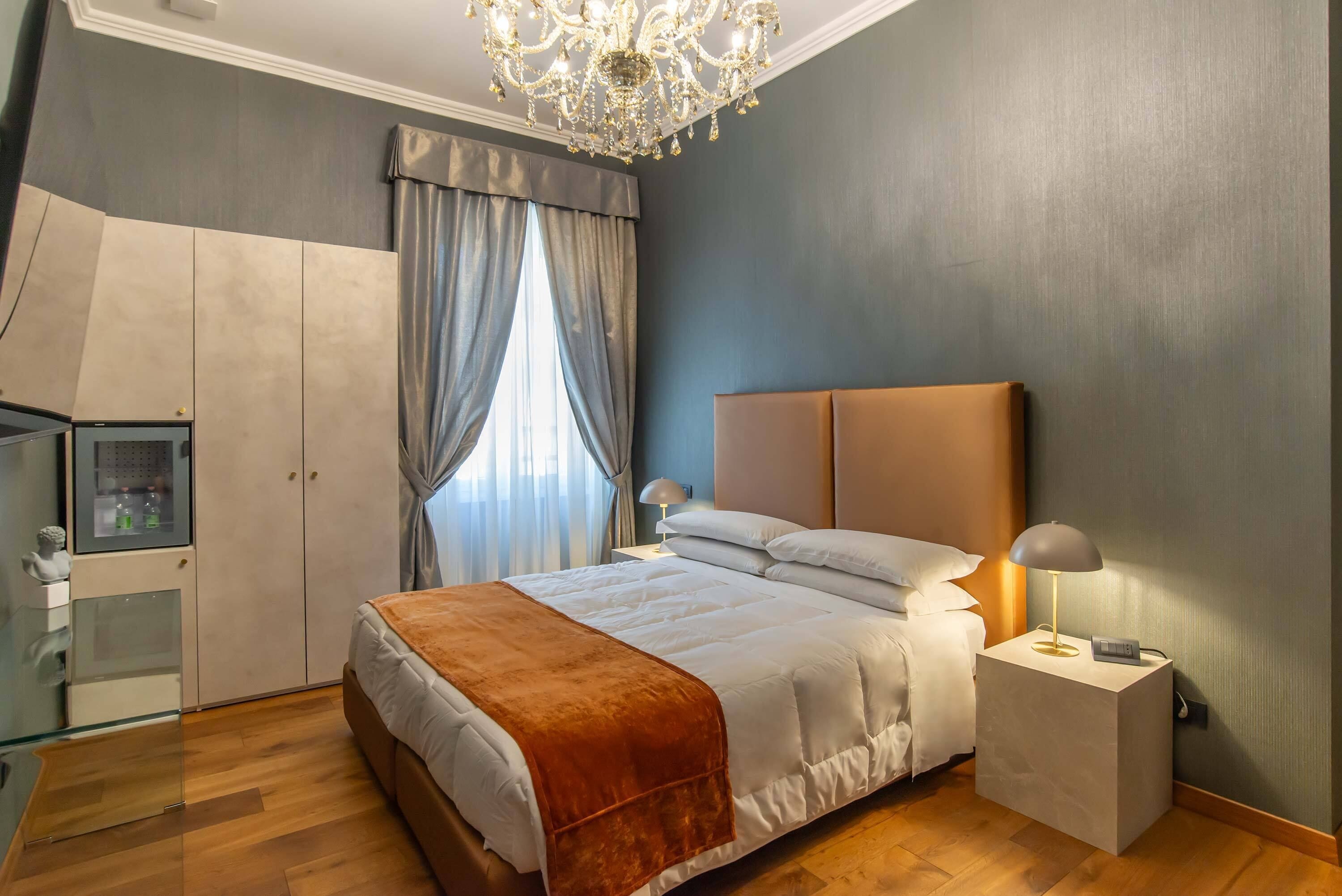 Un dormitorio con cama, mesita de noche, lámpara, armario y vitrina de vidrio.
