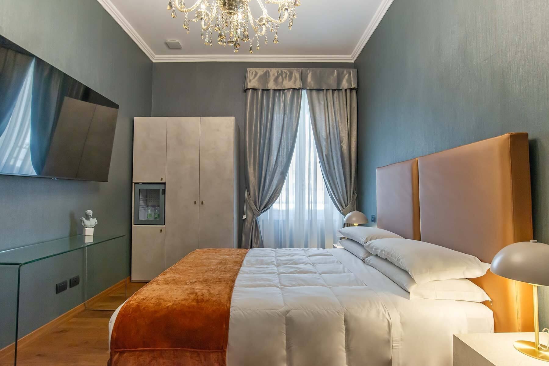A modern bedroom with a large bed, a glass cabinet, a television, and a chandelier.