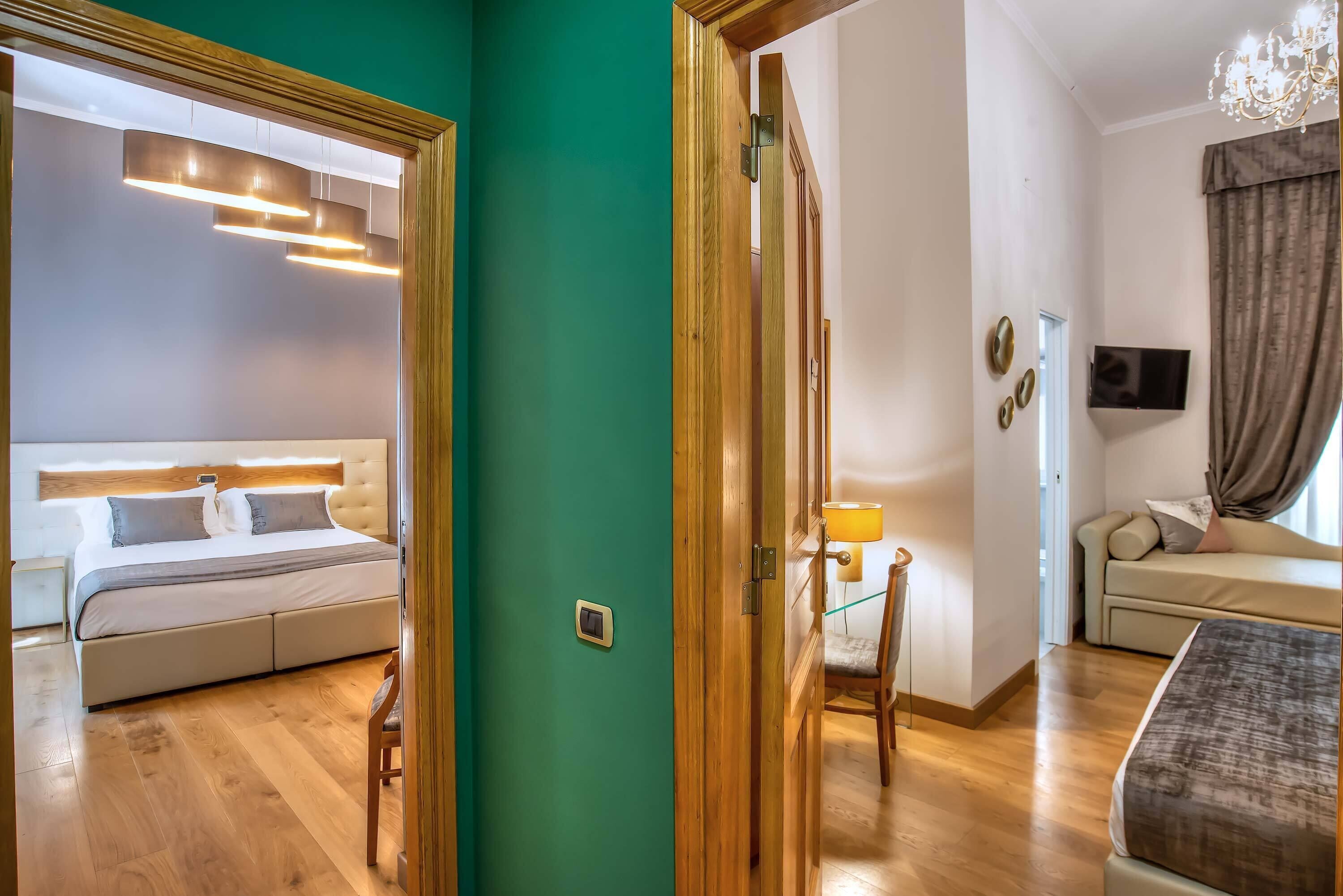 A hotel room with a bed, a sofa, a TV, and a lamp.