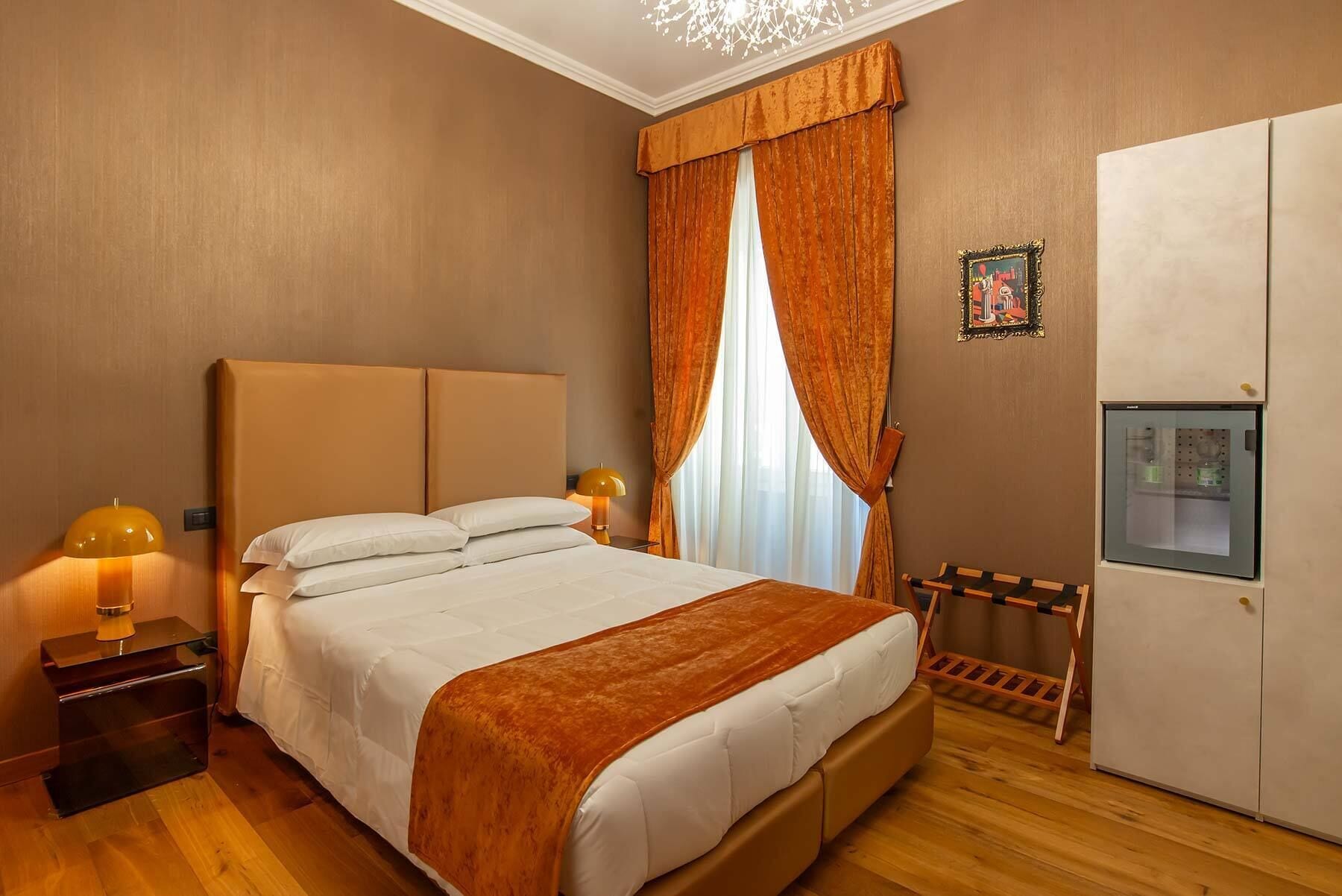 Une chambre d’hôtel avec un grand lit, une armoire, une petite table avec une lampe et un radiateur.
