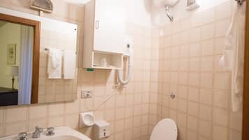 A small bathroom with a sink, toilet, bidet, and a mirror.