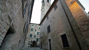 Un callejón estrecho con edificios de ladrillo, una torre y un letrero que dice "DOLCI".