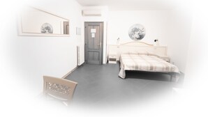 Un dormitorio con cama, mesitas de noche, un espejo y una puerta.