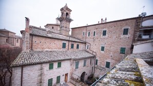 Un edificio histórico con una torre de campanas, paredes de ladrillo y contraventanas verdes.