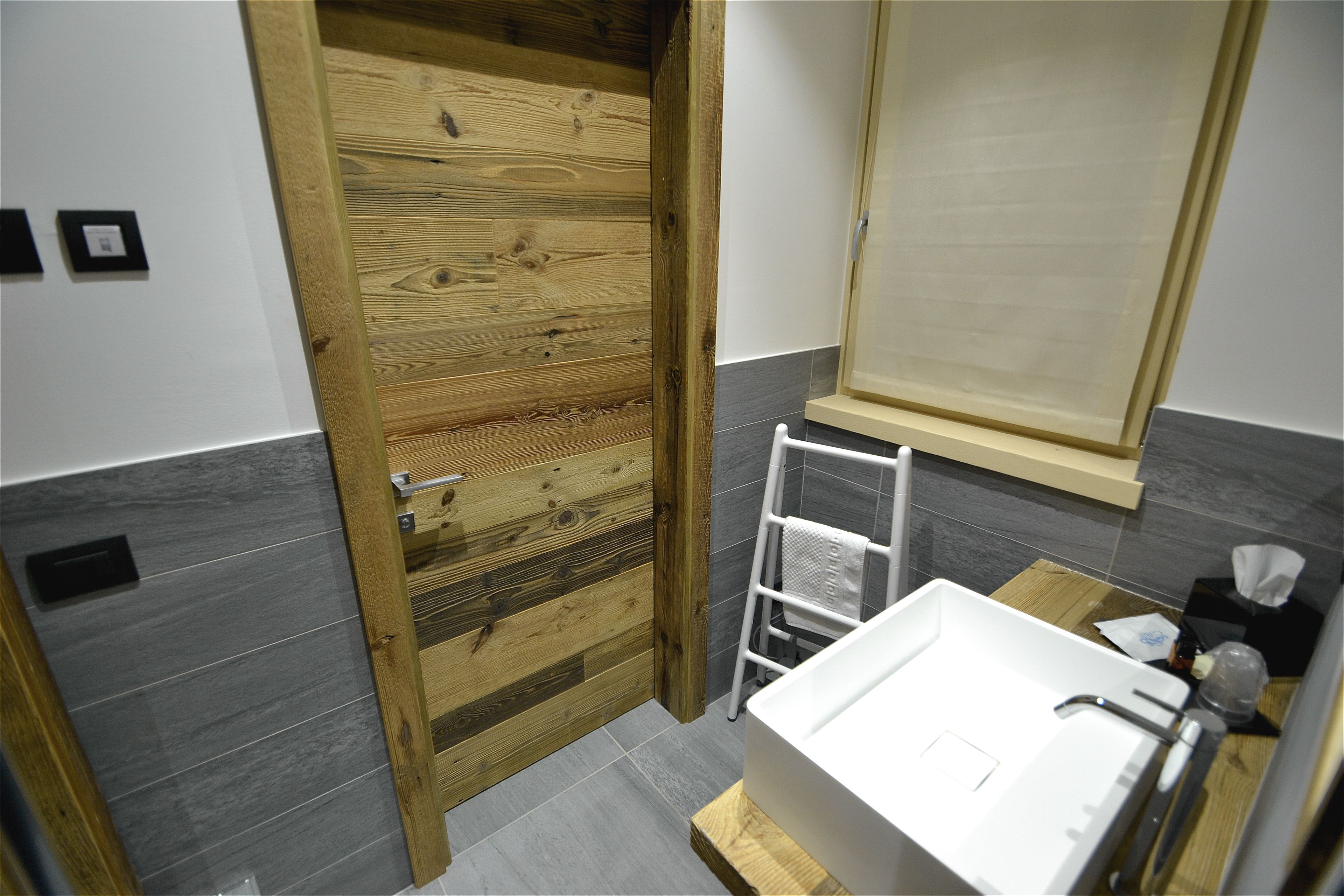 Ein Badezimmer mit Holztür, Waschbecken in Weiß und einem Handtuchhalter.