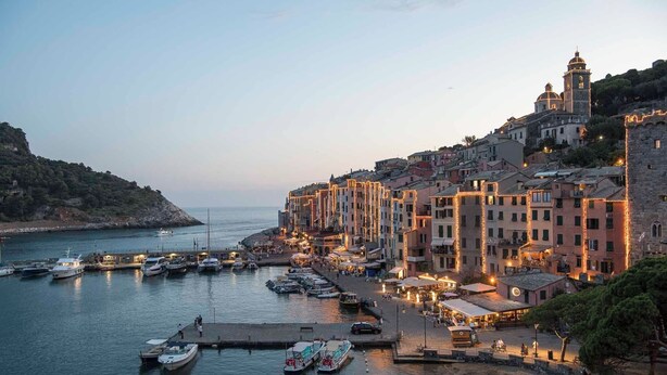 Un pueblo costero con edificios históricos, un puerto deportivo con barcos y una imponente torre de iglesia.