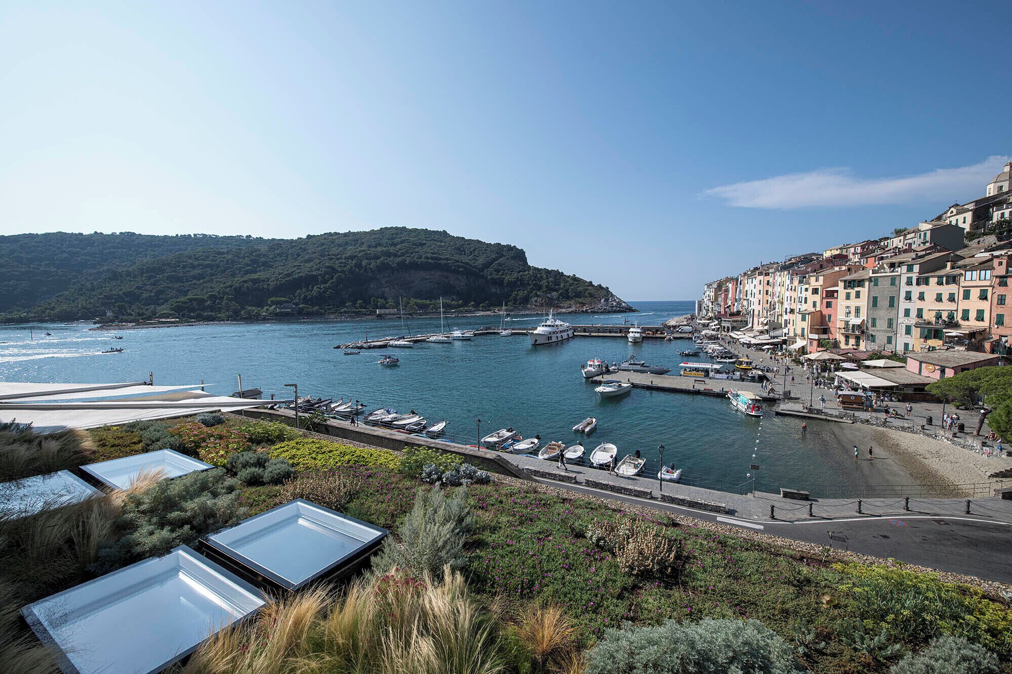 A coastal town with a marina, waterfront buildings, and a hillside.
