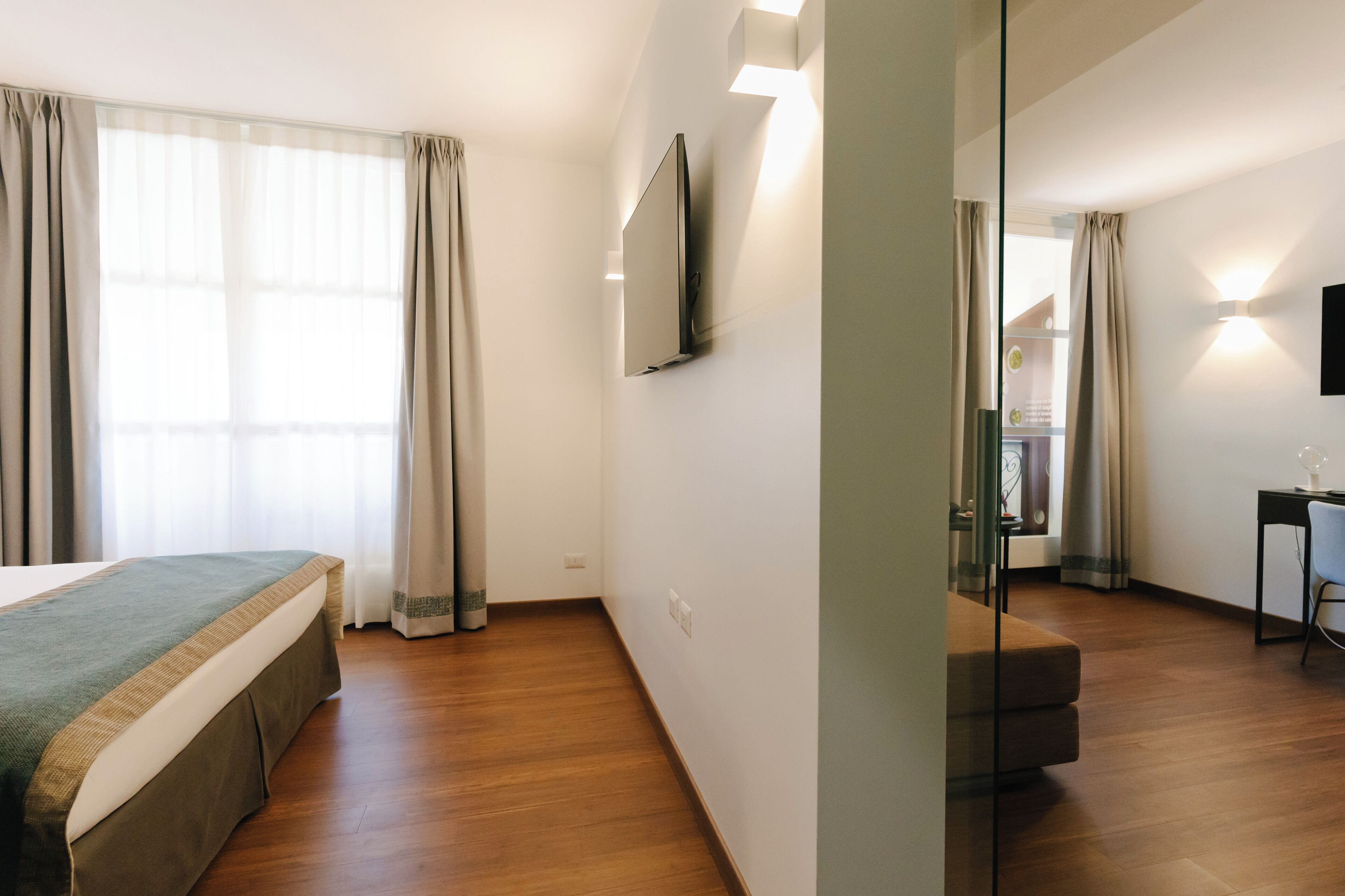 Une chambre d’hôtel équipée d’un lit, d’un bureau et d’un téléviseur fixé au mur.