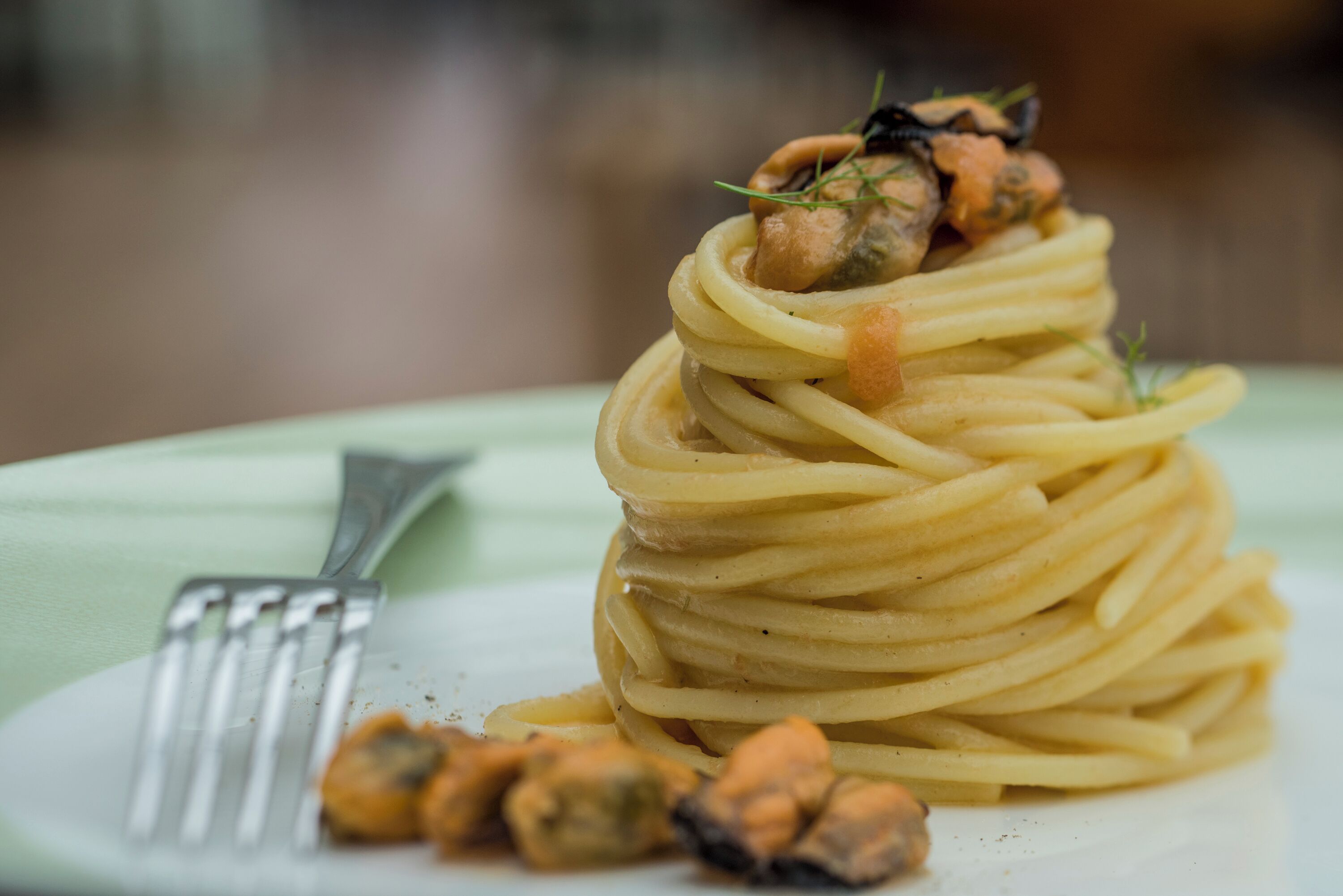Une assiette de spaghettis, recouverte d’une généreuse portion de sauce, avec une fourchette à côté.