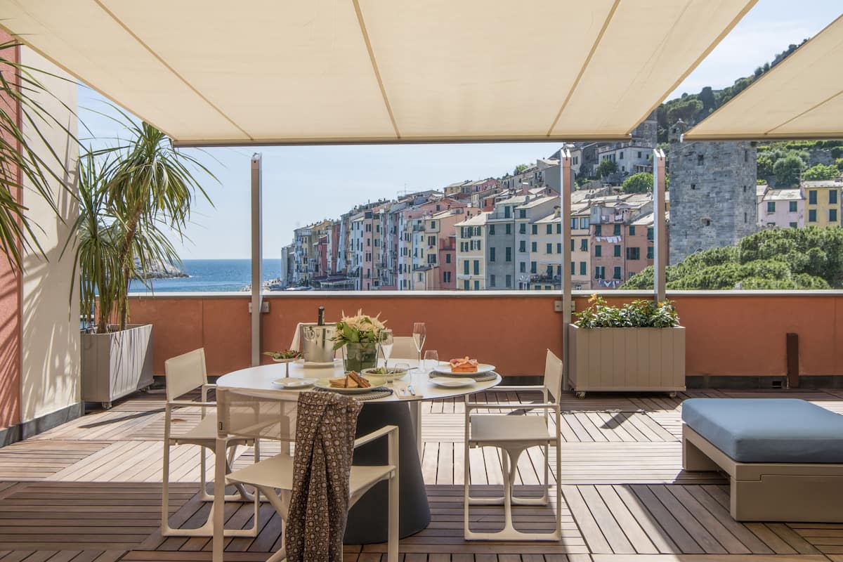 Eine Terrasse mit Esstisch, Stühlen, einer Couch und Kübelpflanzen.