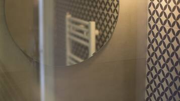 A bathroom with a round mirror, a sink, and a wall with a geometric tile pattern.