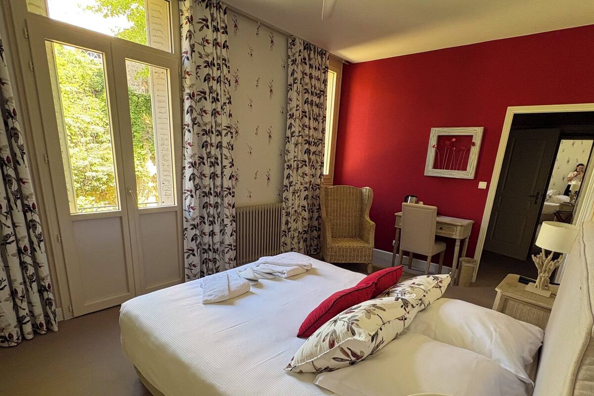 Un dormitorio con una cama, una silla, un escritorio, un espejo y un ventilador de techo.