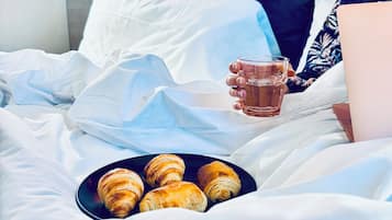 Iemand ligt in bed met een bord croissants en een kop thee.