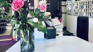 Un mostrador de recepción con un florero, un teléfono y un tablón de anuncios con tarjetas de identificación.