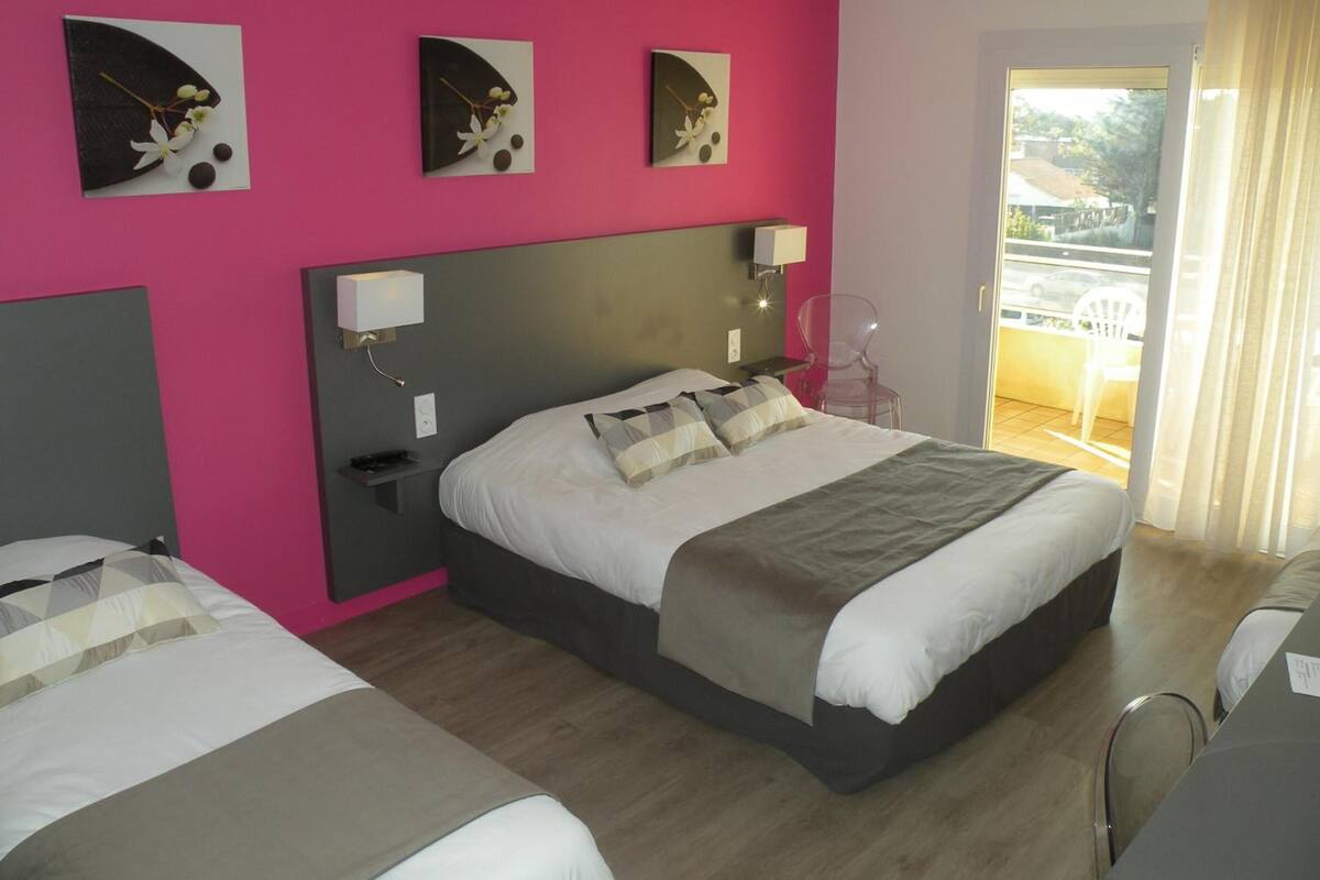 A hotel room with a large bed, a bedside table, a chair, and a balcony with a view.