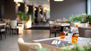 Een restaurantinterieur met gedekte tafels, sfeerverlichting en binnenshuis planten.