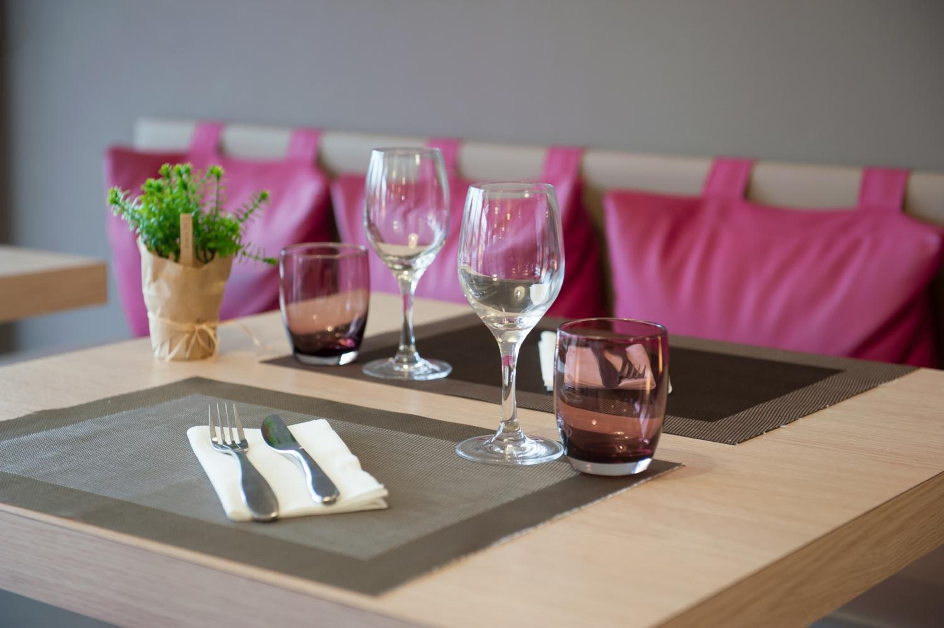 A dining table with a placemat, cutlery, and wine glasses.