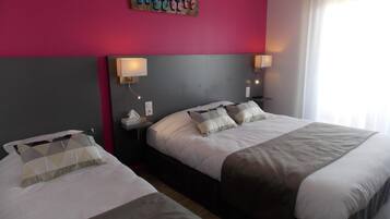 A hotel room with two beds, a pink accent wall, and a painting above the beds.