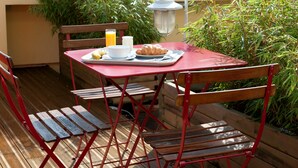 Een rode tafel met een dienblad vol croissants, een glas sinaasappelsap en een kop koffie.