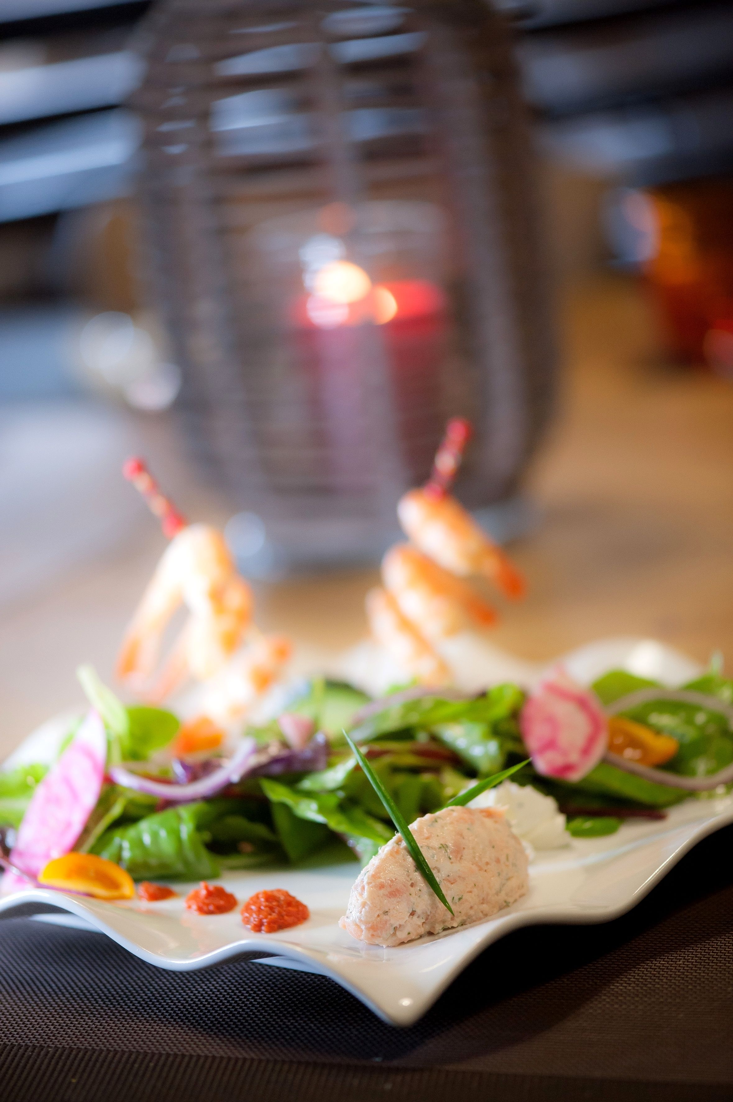 Une assiette de nourriture comprenant des brochettes de crevettes et une salade.