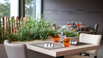 Een eetgedeelte met een tafel gedekt voor twee personen, bestaande uit een houten tafel, twee stoelen en een klein plantenarrangement.