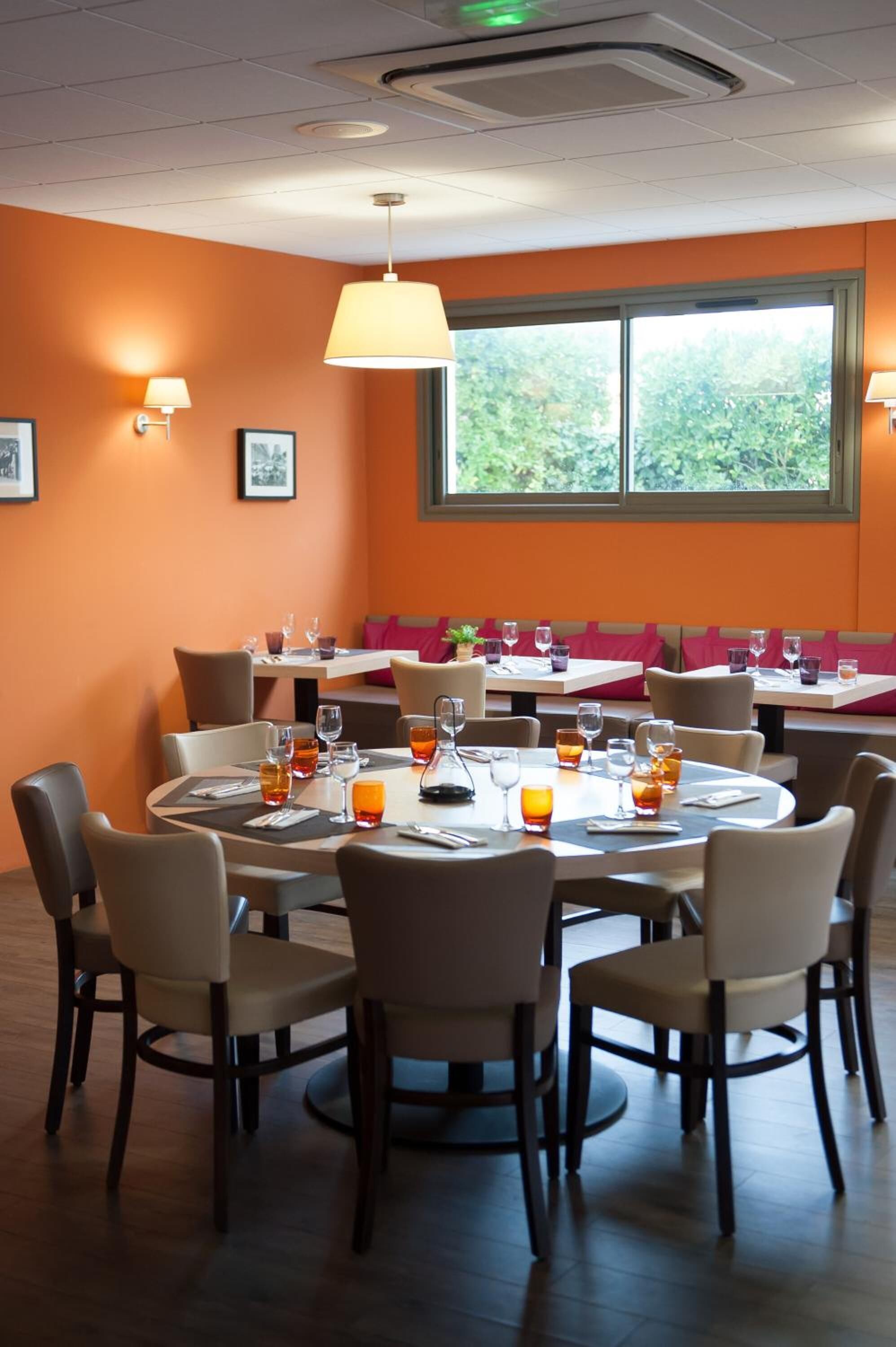 Comedor con mesas redondas, sillas y paredes anaranjadas.