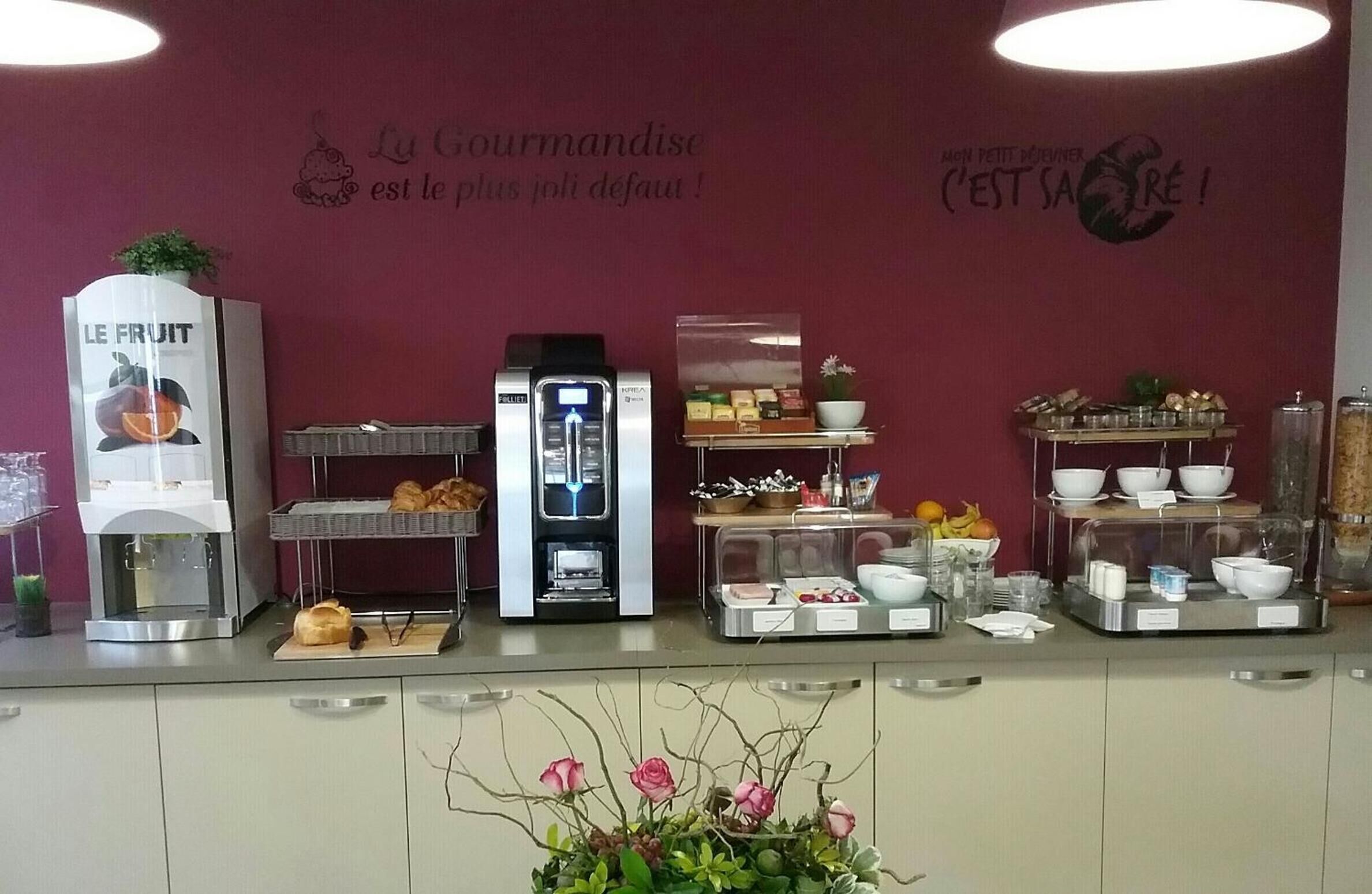 Una barra de desayuno con una máquina de café, una exposición de fruta y una variedad de alimentos.