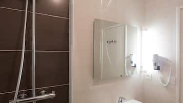 Un baño moderno con ducha envuelta en vidrio, un lavabo blanco y un espejo.