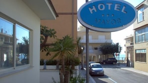 Placa de hotel com o nome 'HOTEL MAYOR' e uma palmeira em primeiro plano.