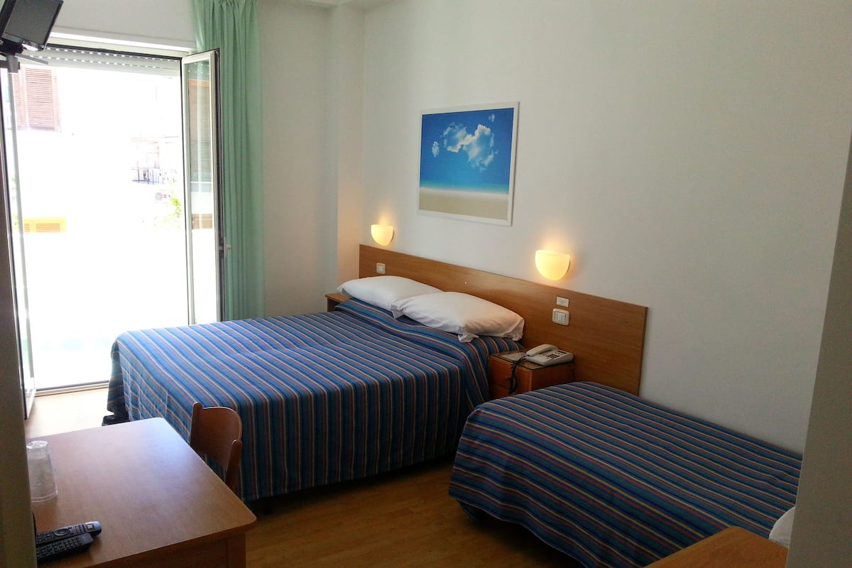Ein Hotelzimmer mit zwei Betten, einem Schreibtisch und einem Stuhl.