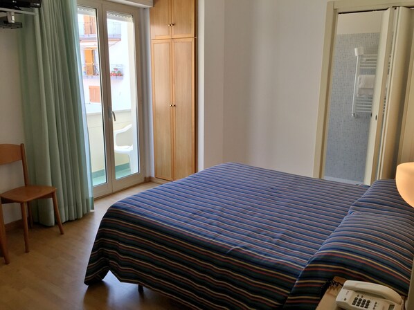 Un dormitorio con cama, una silla, un armario y la puerta del baño.