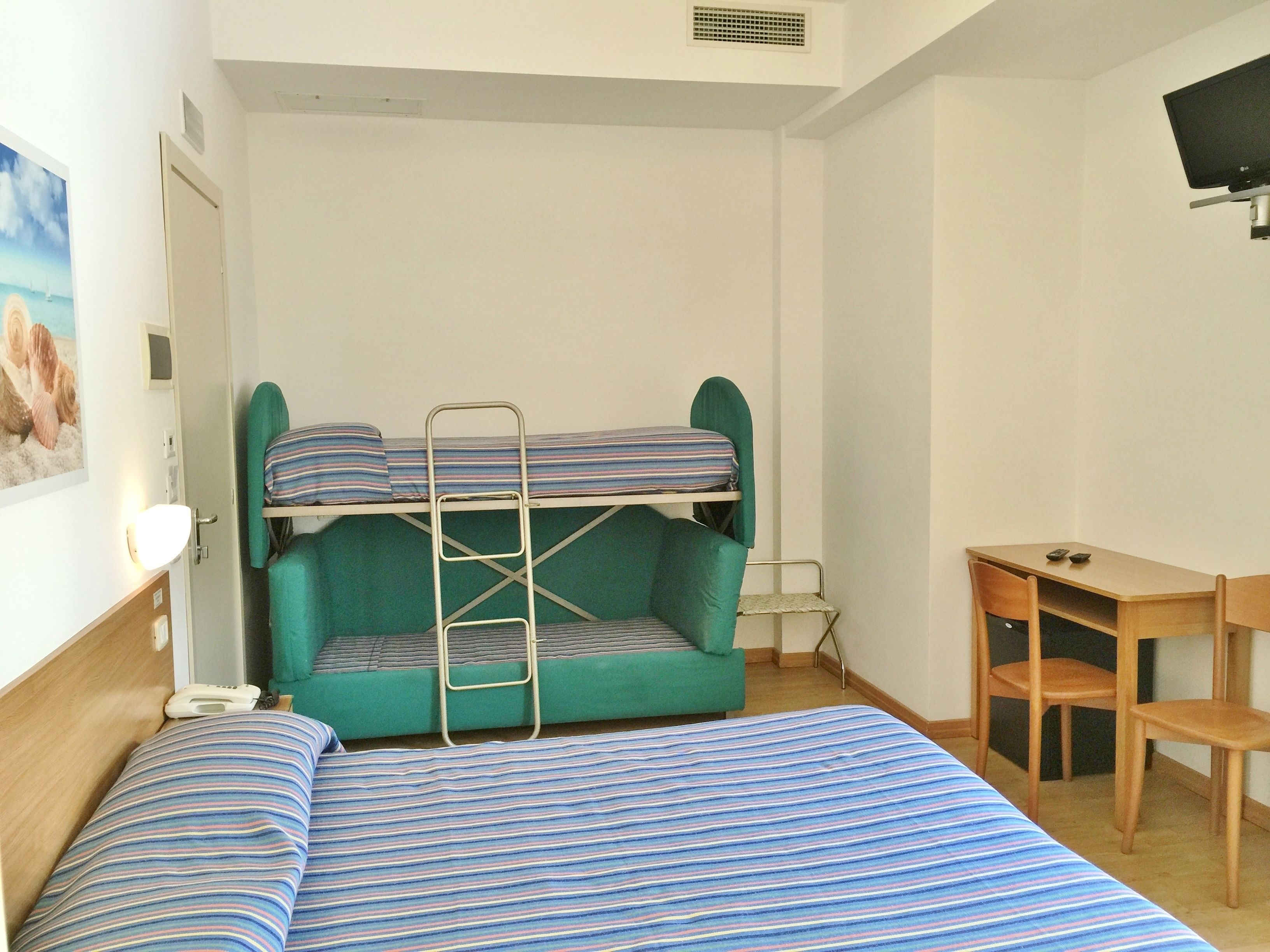 Une chambre avec un lit superposé, un bureau et un téléviseur.