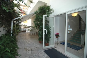 An entrance with a glass door, a staircase, and potted plants.