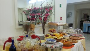 Uma mesa de buffet com diversas opções de comida, incluindo frutas, doces e acompanhamentos.