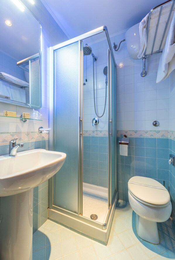 Un baño con ducha envuelta en vidrio, lavamanos e inodoro.