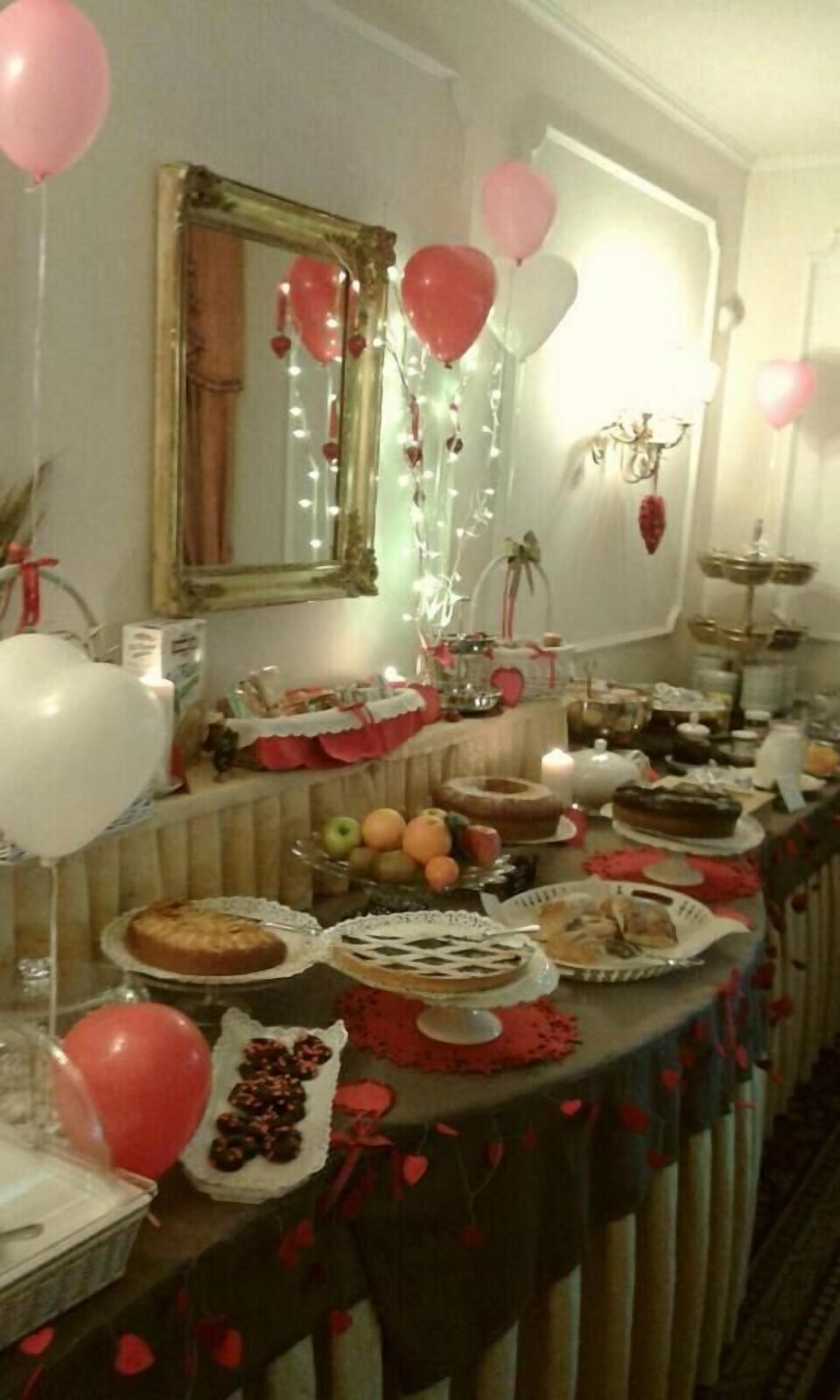 A buffet table with various dishes, balloons, and a mirror on the wall.