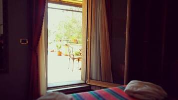 A room with a bed, a window with curtains, and a view of the outside.
