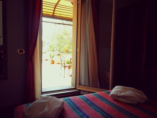 A room with a bed, a window with curtains, and a view of the outside.