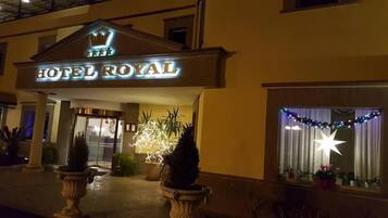 Exterior del Hotel Royal con un llamativo letrero iluminado, una entrada imponente y iluminación decorativa.