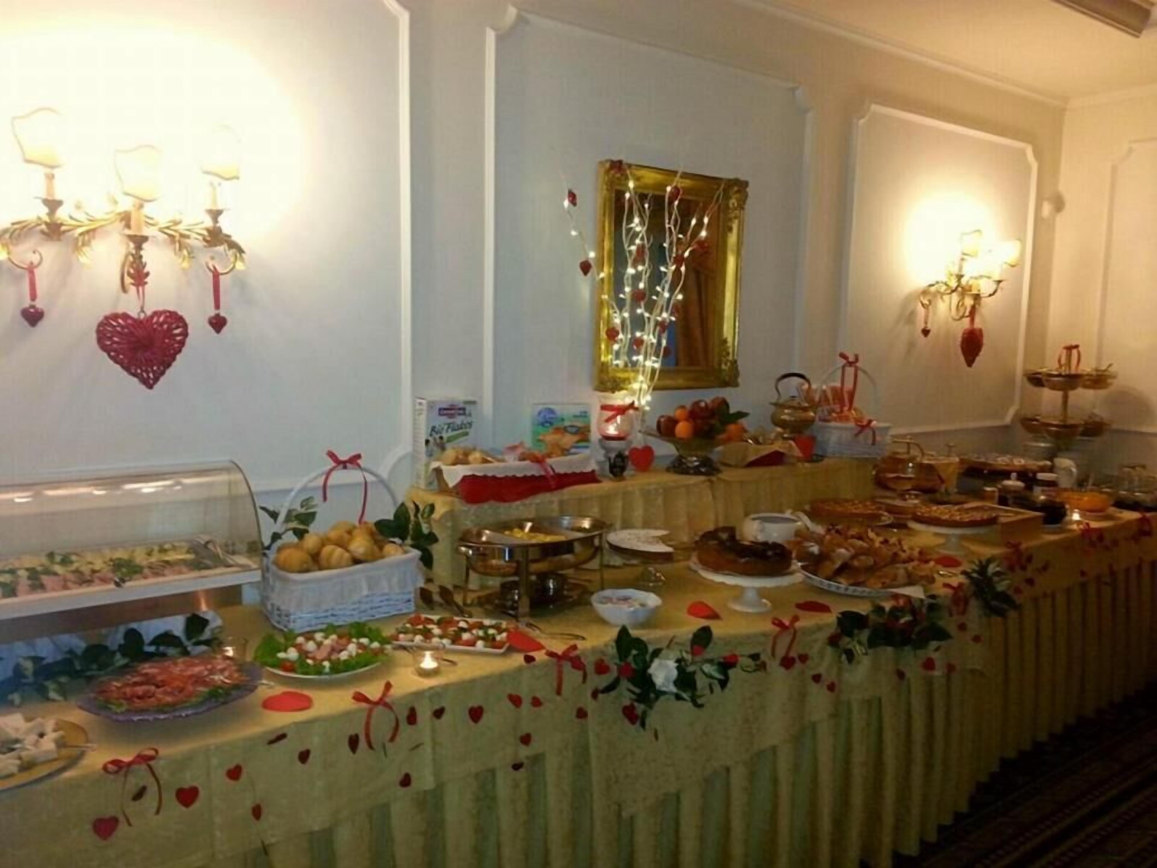 Une table de buffet garnie de divers plats et décorations, notamment des ornements en forme de cœur et un miroir avec un cadre doré.