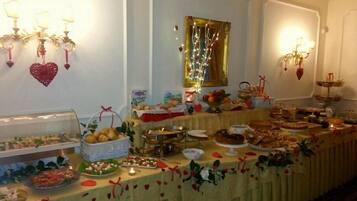 Une table de buffet garnie de divers plats et décorations, notamment des ornements en forme de cœur et un miroir avec un cadre doré.