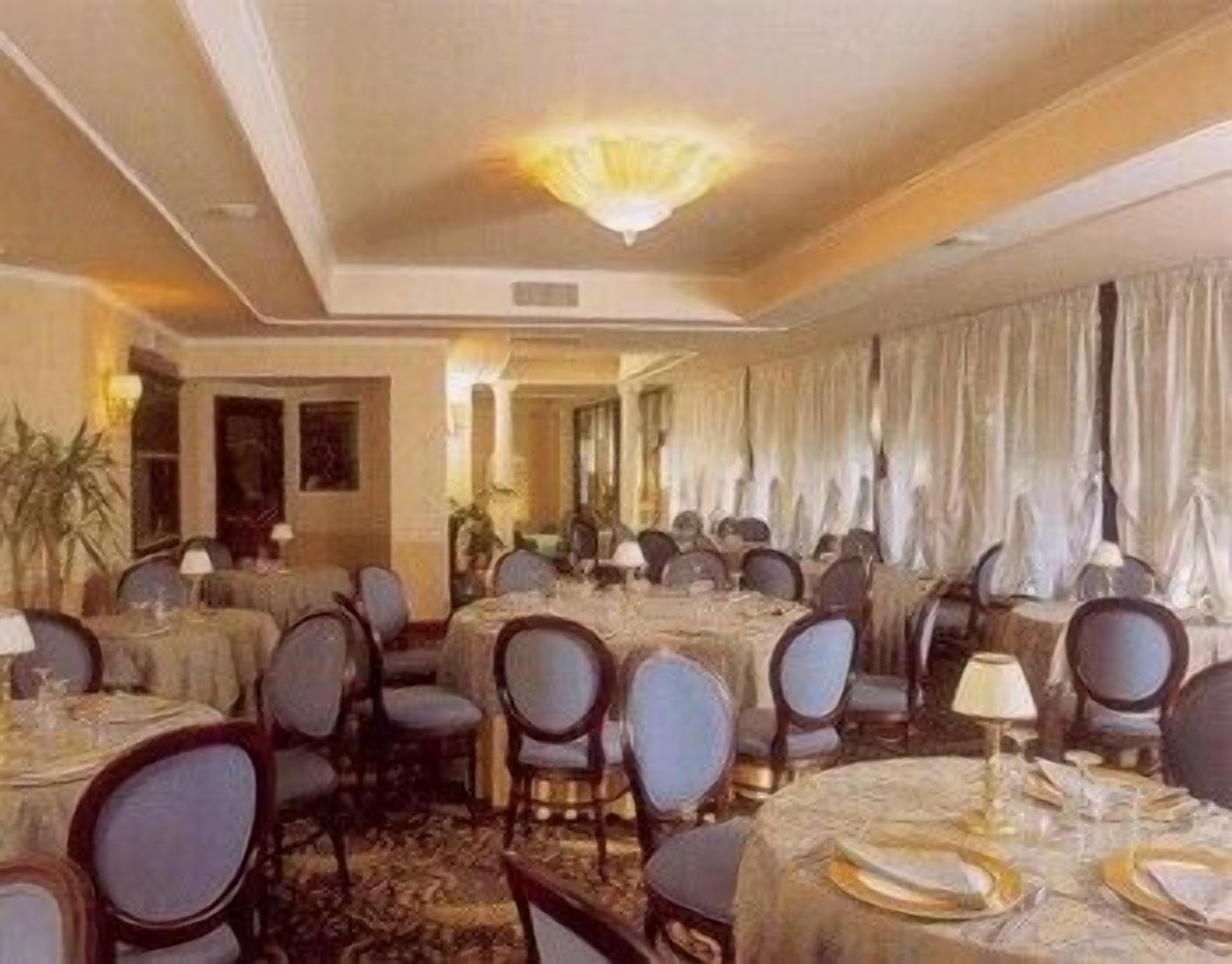A formal dining room with round tables, chairs, and chandeliers.