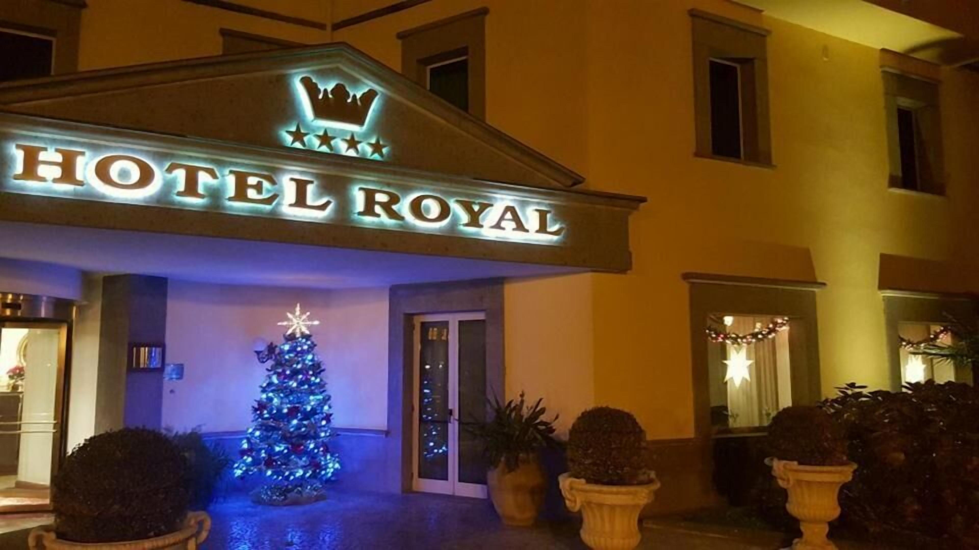 A hotel entrance with a sign reading "HOTEL ROYAL" and a lit Christmas tree.