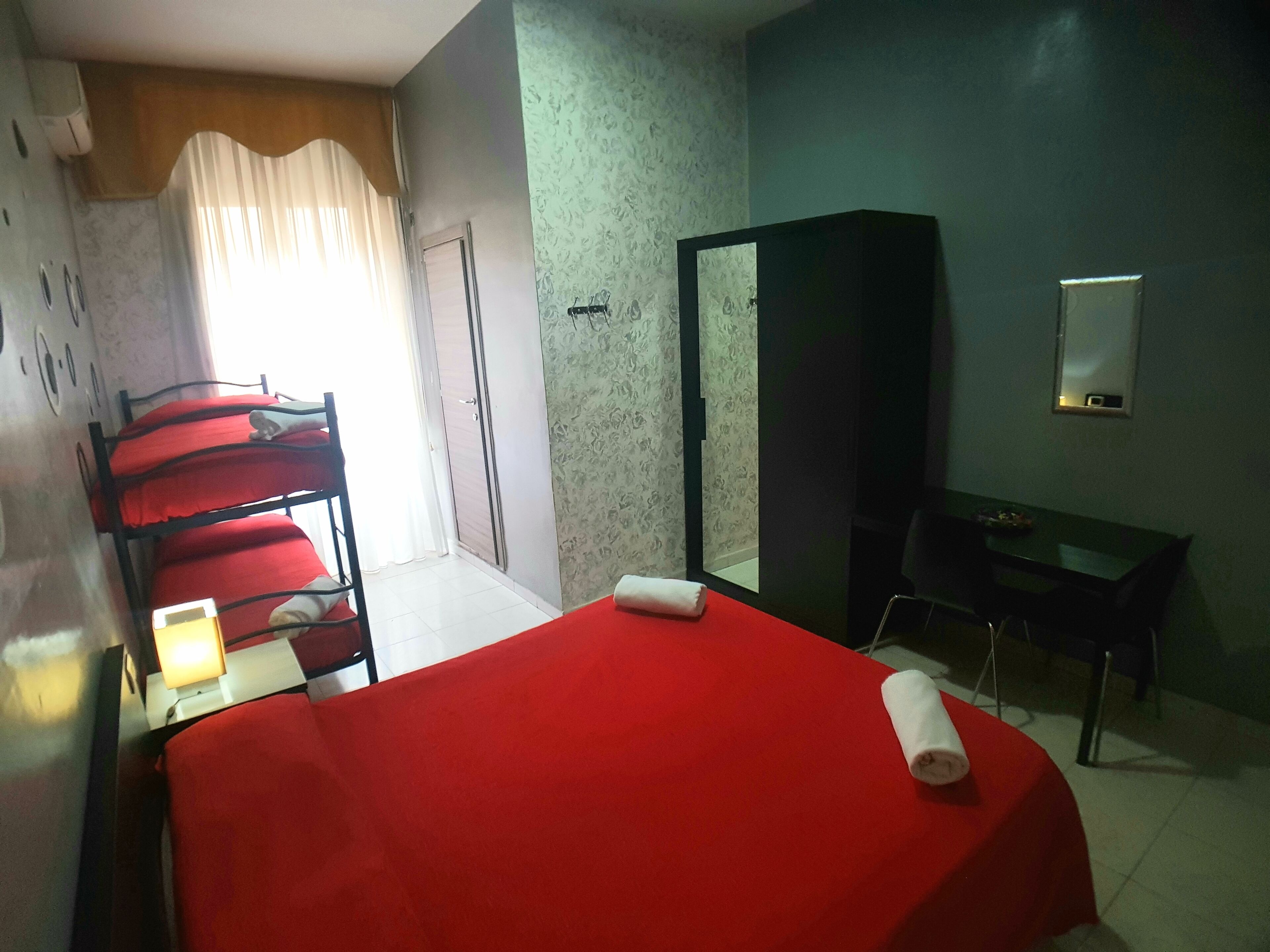A hotel room with a bed, a desk, a wardrobe, and a mirror.