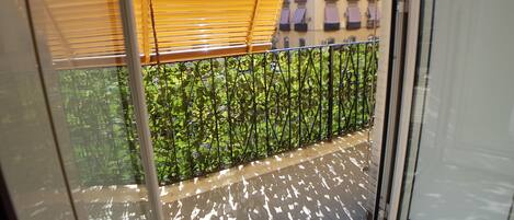 A balcony with a metal railing, a yellow awning, and a view of a building with balconies.