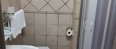A bathroom with a toilet, sink, and shower.