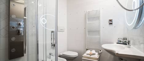 Um banheiro moderno com box de vidro, vaso sanitário branco, pia e espelho com iluminação embutida.