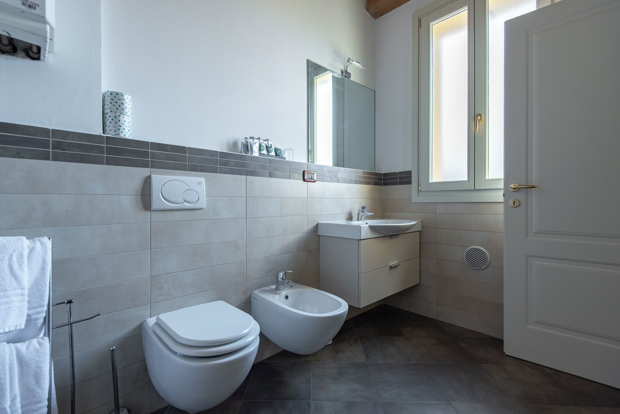 A modern bathroom with a toilet, bidet, and sink.